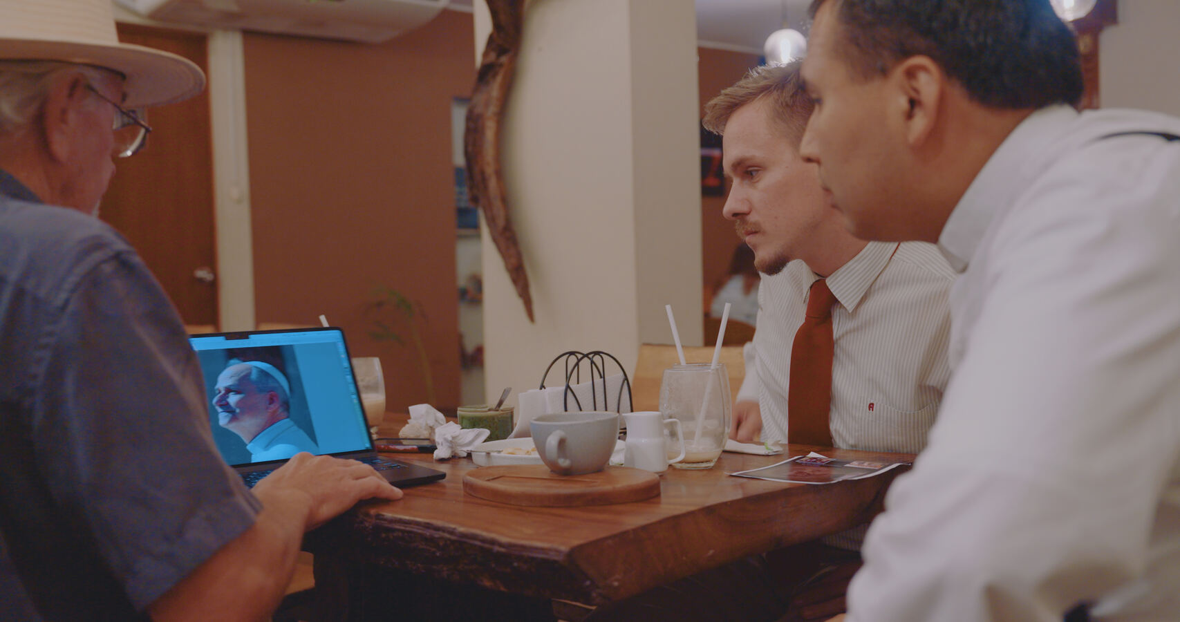 Stan Herd shows the portrait design on a laptop to Louis and Father Cesar