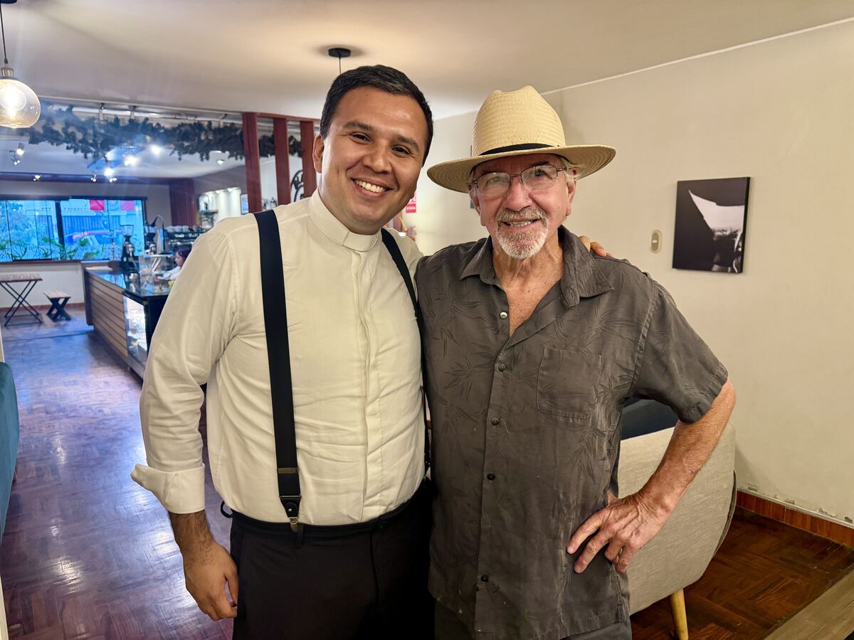 Father Cesar and Stan Herd smiling together in a restaurant