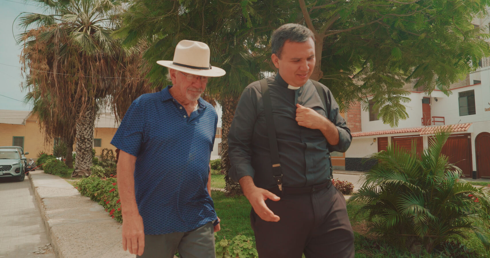 Stan Herd and Father Cesar walking a tree-lined street in Chiclayo