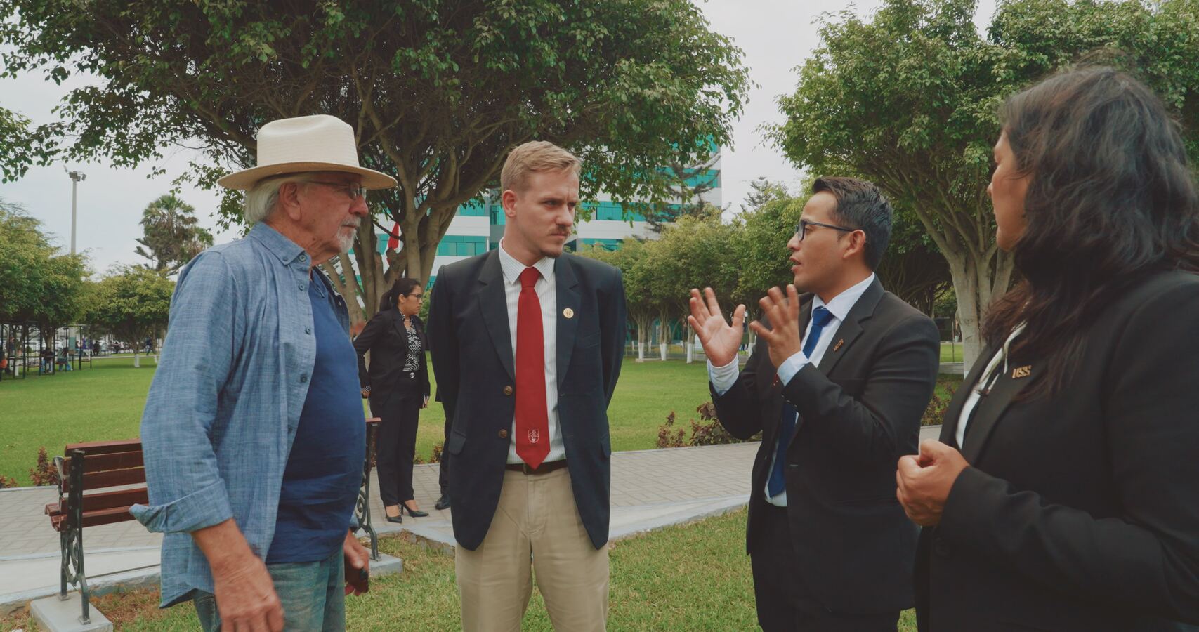 Stan Herd talking with Louis, Jhon and a colleague on a campus lawn